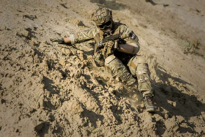 Soldier in camouflage uniform with weapon on sandy slope
