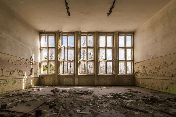 Abandoned building interior with broken windows and debris