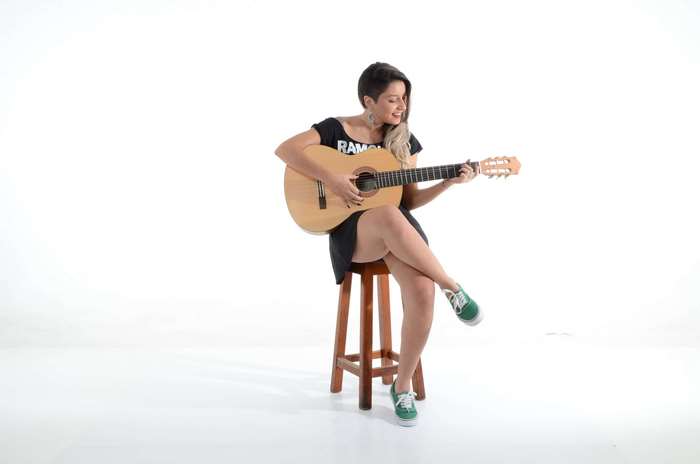 Woman playing guitar on a stool
