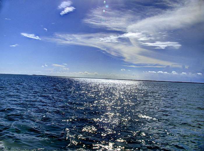 Atlantic Ocean waves with sun glare and clouds