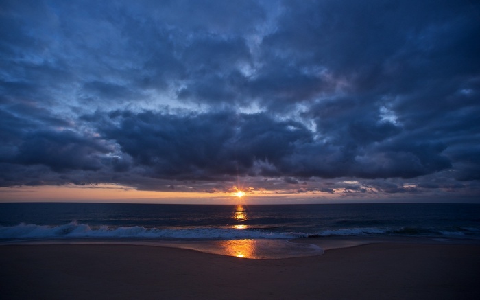 Sunset over the ocean with dark clouds