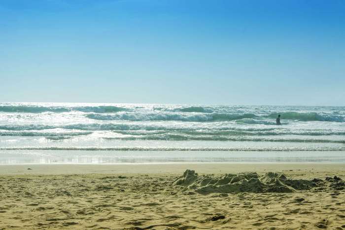Beach landscape with waves and a person in the ocean