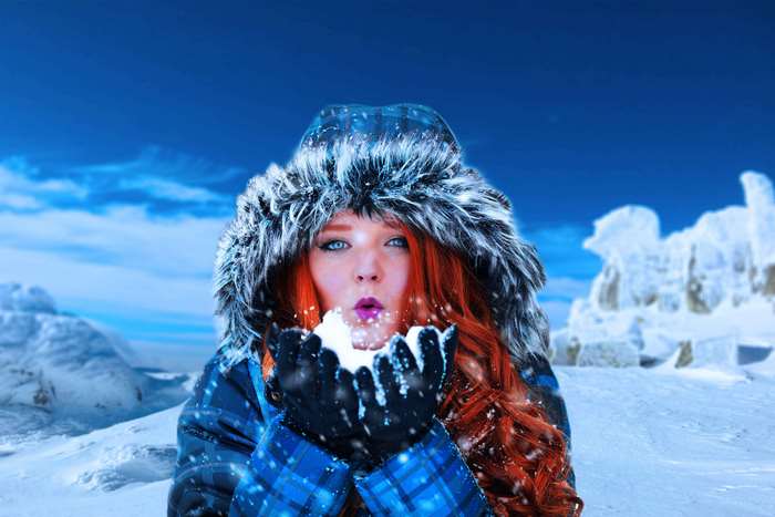 Woman in winter coat blowing snow