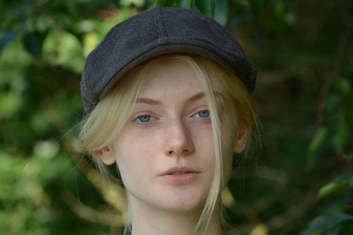 Young woman with blonde hair wearing a cap outdoors