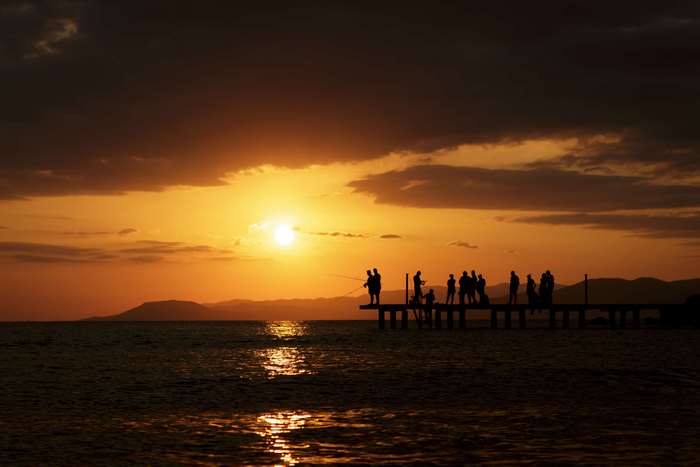 People fishing on a pier at sunset 4K