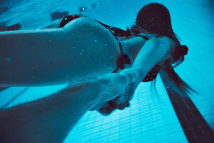 Couple holding hands underwater in a swimming pool