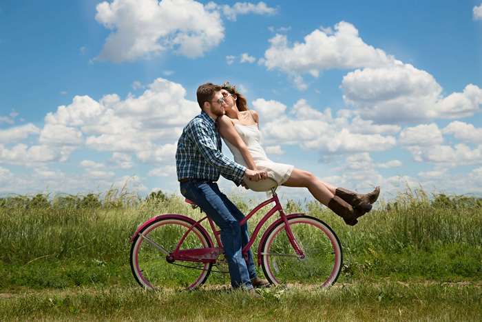 Couple kissing on a bicycle in a field