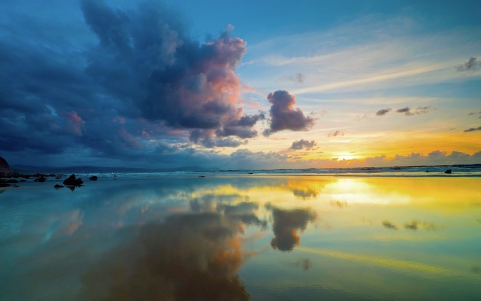 Sunset over the ocean with dramatic clouds and reflections
