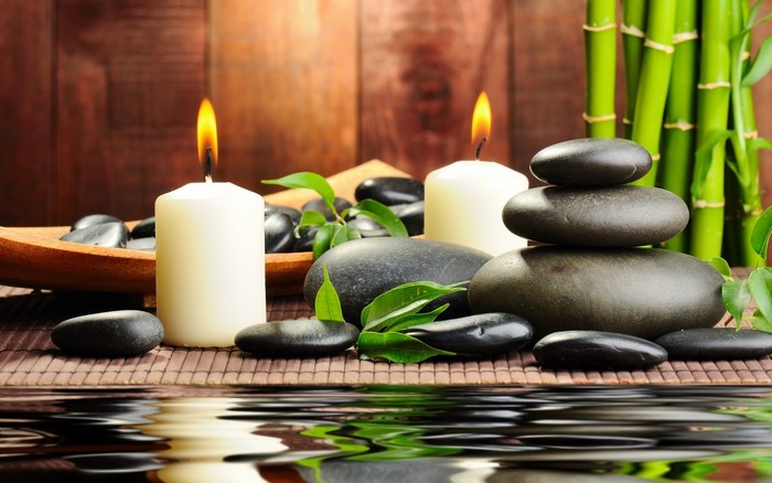 Spa setting with candles, stones, and bamboo