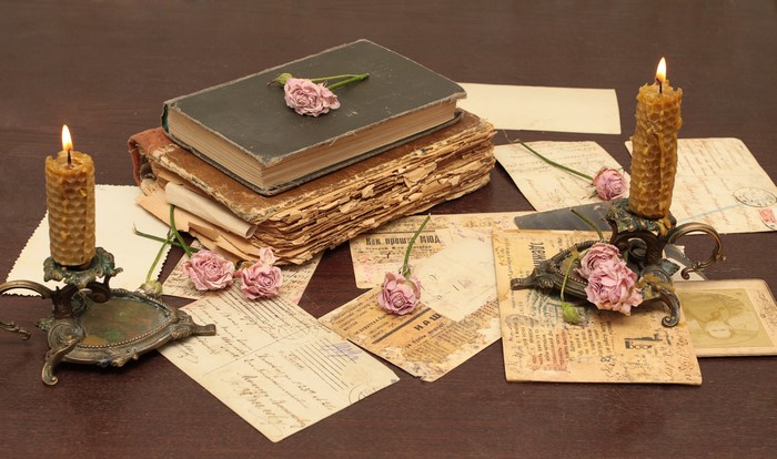 Vintage books, roses, letters, and candles on a table