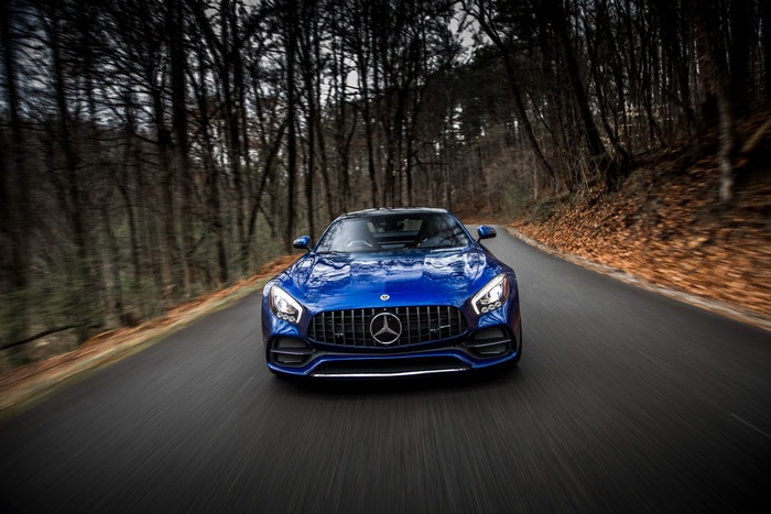 Blue Mercedes-AMG GT C driving on a forest road