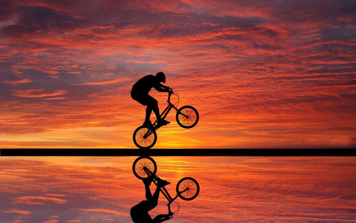 BMX rider silhouetted against a sunset sky