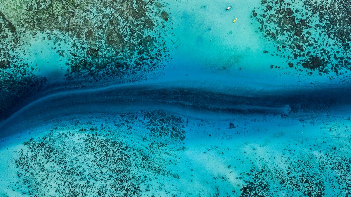 Drone view of ocean with coral reefs and kayaks