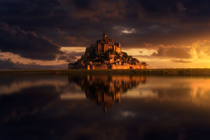 Mont Saint-Michel monastery reflected in water at sunset