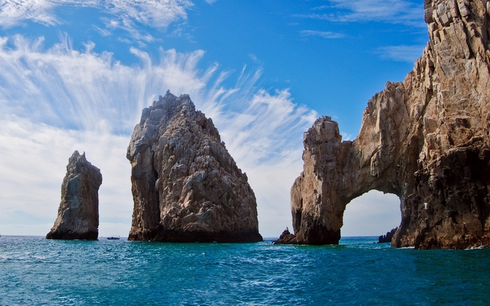 Rock formations in the ocean under a blue sky