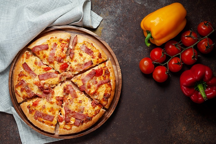 Pizza with bacon and tomatoes, bell peppers, and tomatoes
