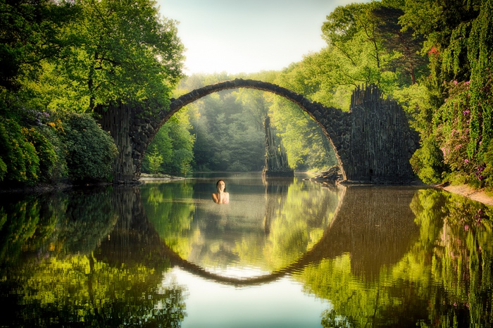 Devils Bridge Over Calm River with Woman Swimming