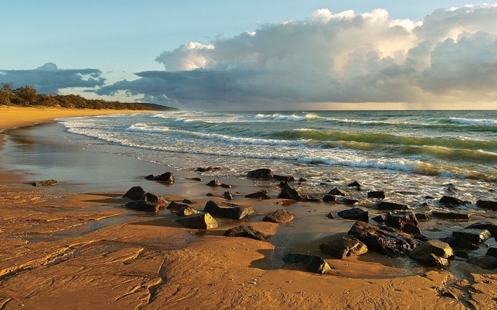 Beach with waves and rocks at sunset