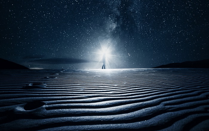 Person standing in desert under starry sky