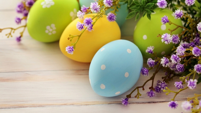 Easter eggs with purple flowers on wooden background
