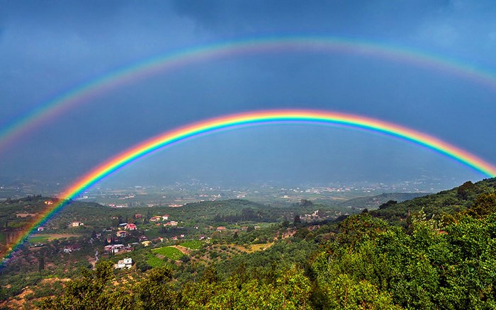 Double rainbow over green hills