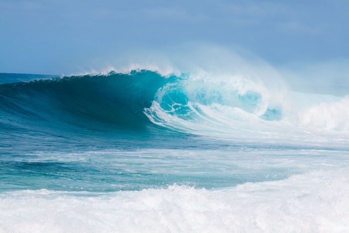 Ocean wave crashing with blue sky