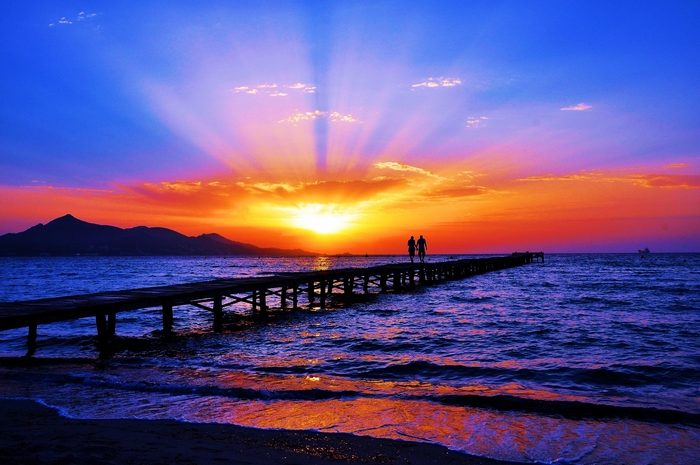 Couple walking on pier during sunset