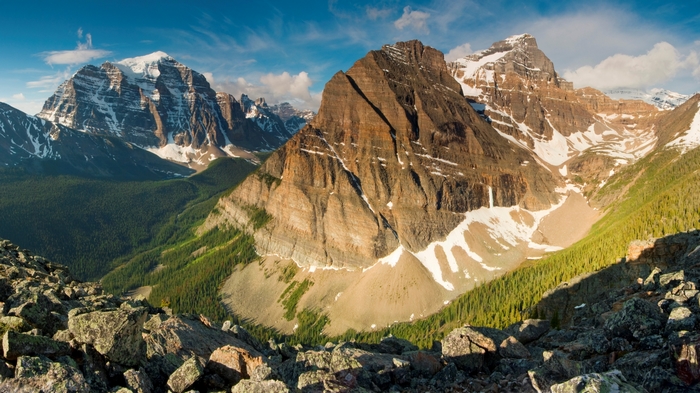 Rocky mountain range with snow-capped peaks and green forest