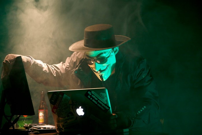 Anonymous hacker wearing Guy Fawkes mask and hat