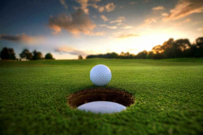 Golf ball on a golf course near a hole at sunset