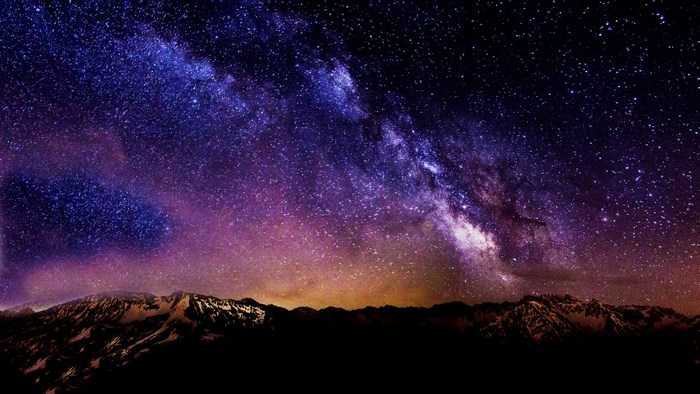 Milky Way Galaxy over snow-capped mountains at night