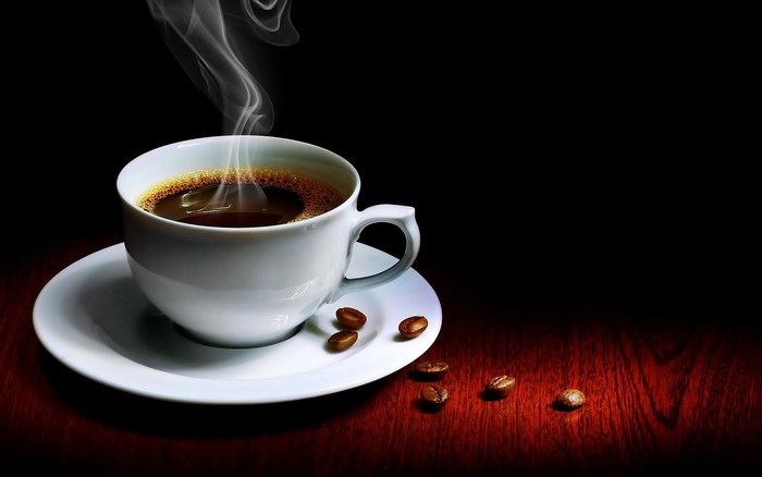 Steaming cup of coffee with beans