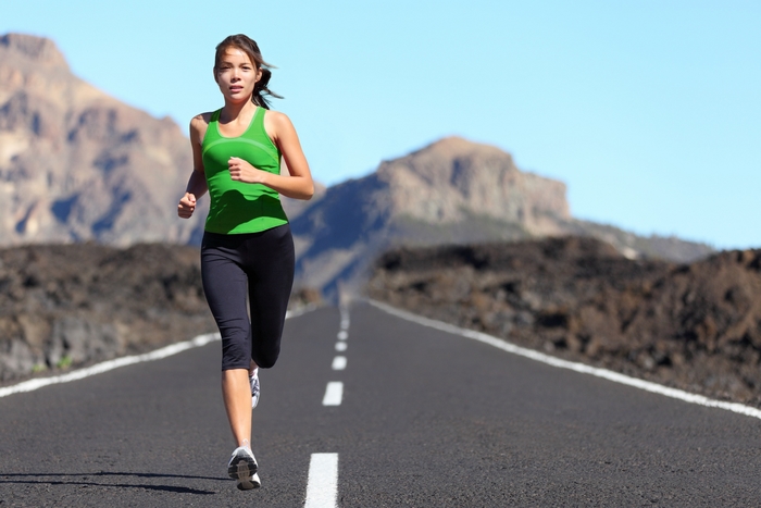 Woman running on a road in a mountainous landscape