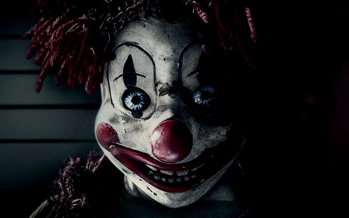 Creepy clown doll with red hair and makeup