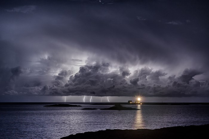 Lightning storm over the sea with a lighthouse