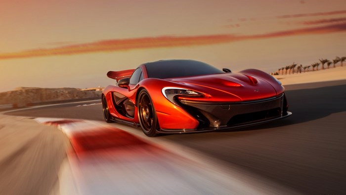 Red McLaren P1 on a race track at sunset