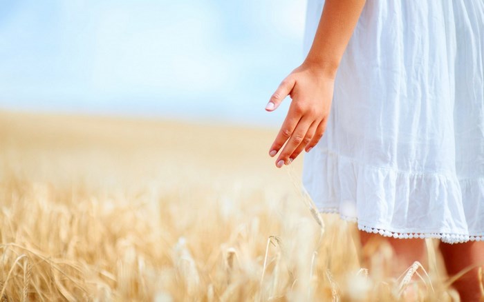 Woman in white dress touching wheat field