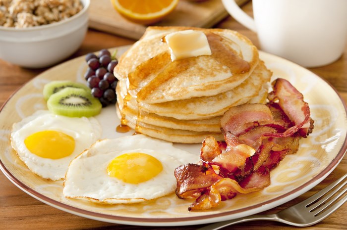 Breakfast plate with pancakes, eggs, bacon, and fruit