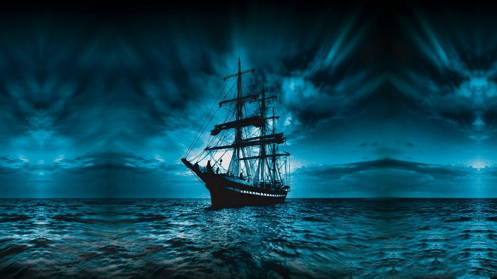 Sailing ship on the ocean under a dark sky