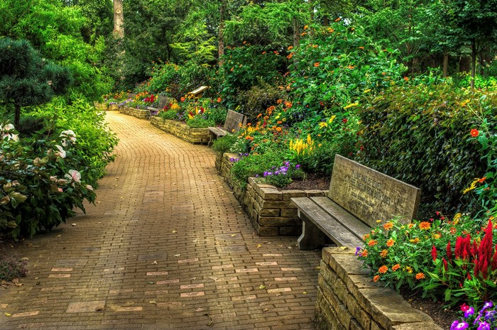 Brick pathway through a garden with benches