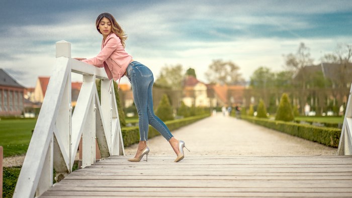 Woman in pink jacket and jeans on bridge