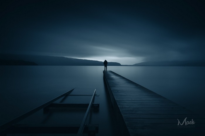 Person standing on a pier at dusk