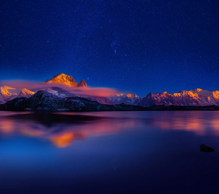Mountains reflected in a lake under a starry sky