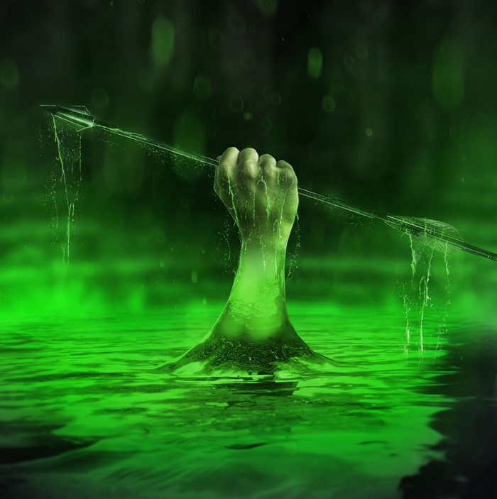Hand holding an arrow emerging from green water