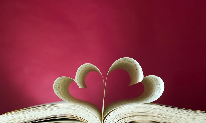 Love hearts made from book pages on a pink background