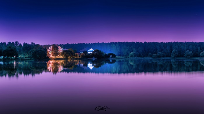 Purple reflections of houses and forest on lake at dusk 4K
