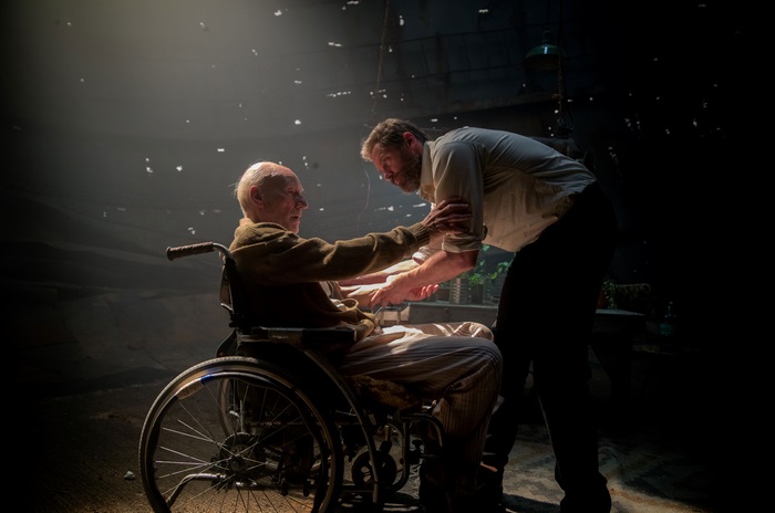Logan in a wheelchair with a man helping him