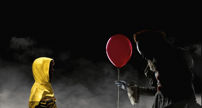 Pennywise the Dancing Clown from It offers a balloon to a child
