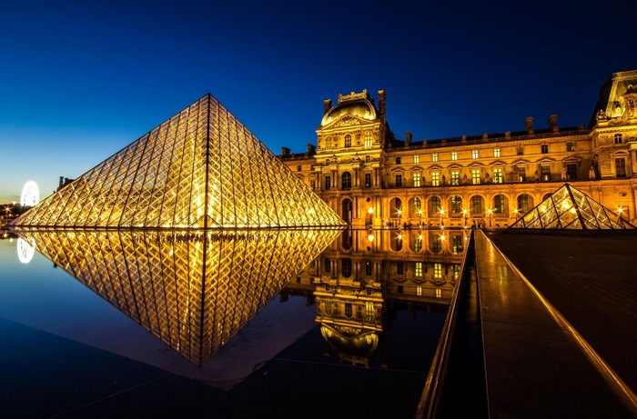 Louvre Museum at night with pyramid and reflection