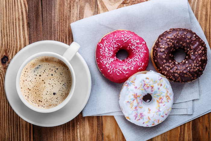 Coffee cup and three donuts on a wooden table